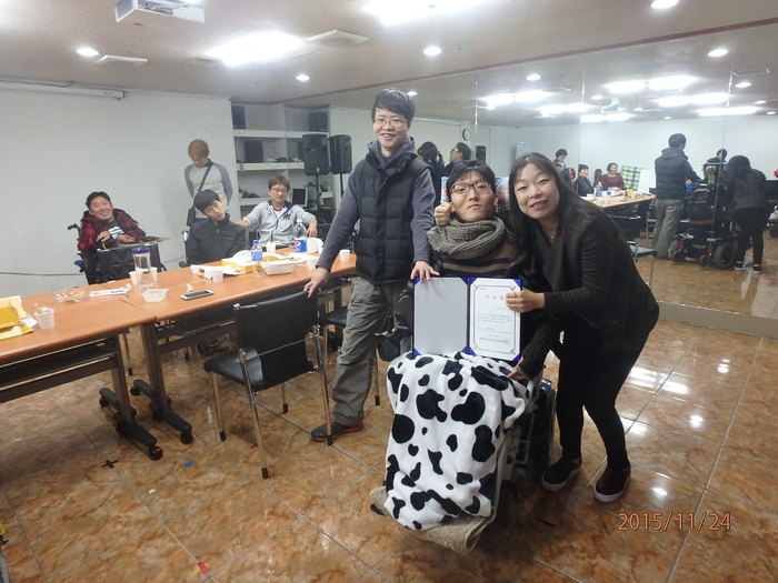 수료증을 들고 있는 정현욱 참가자와 활동지원인 그리고 김정미 소장님과 함께 사진 찍는 모습
