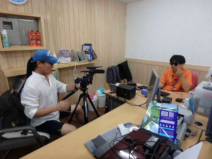 이상훈 팀장이 앉아 있고 정승천 기자가 카메라를 촬영하는 모습
