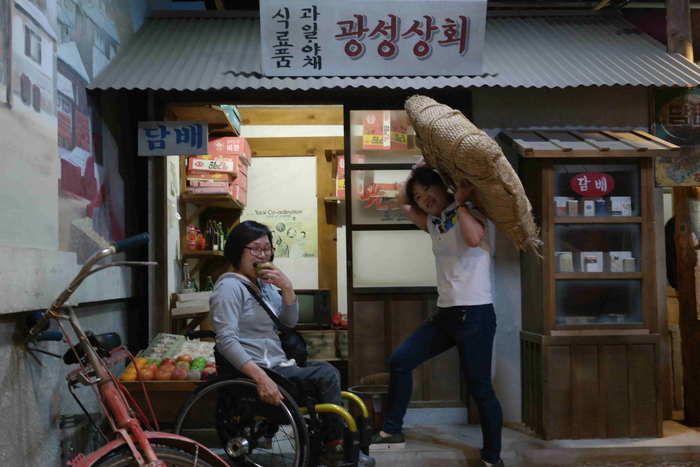 광성상화 앞에서 김정옥 쌀 짊어지고 하윤숙 사과 먹는 사진
