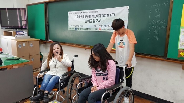 남학생이 휠체어에 앉은 여학생을 밀어주는 모습