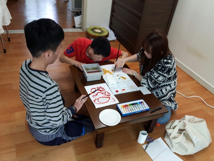 미술심리 치료사가 반영훈의 손을 잡고 함께 그림 그리기를 하는 사진