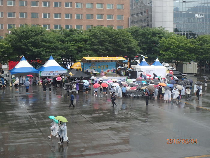 우천으로 공연을 보기위해 비옷을 입고 객석에 않은 관객들 사진