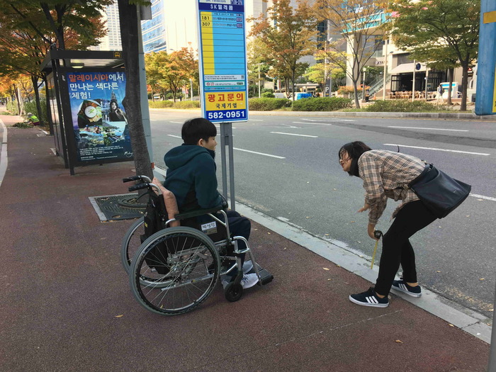 박성민 활동가 앞에 활동지원인이 줄자로 턱 높이는 측정하는 모습