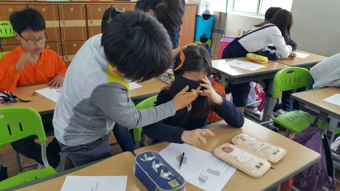 옆의 짝꿍 안대가 제대로 착용했는지 검사하는 학생 모습 옆의 짝꿍 안대가 제대로 착용했는지 검사하는 학생 모습