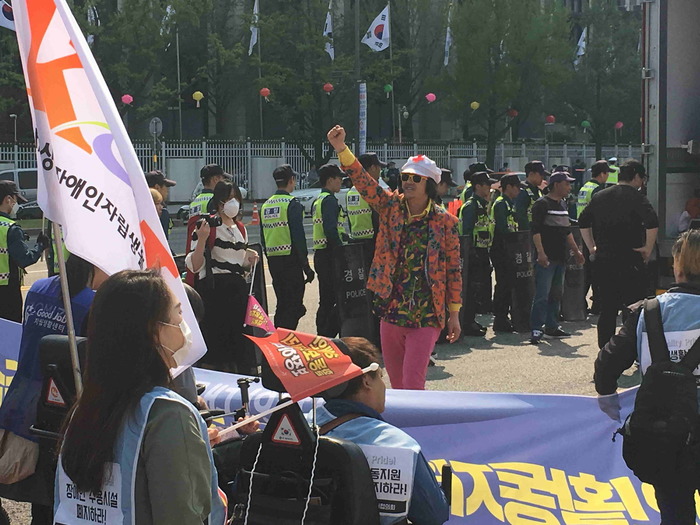 한 남자가 하얀 모자와 검은 썬글라스 눈에 띠는 옷을 입고 오른팔을 위로 들고 있는 모습