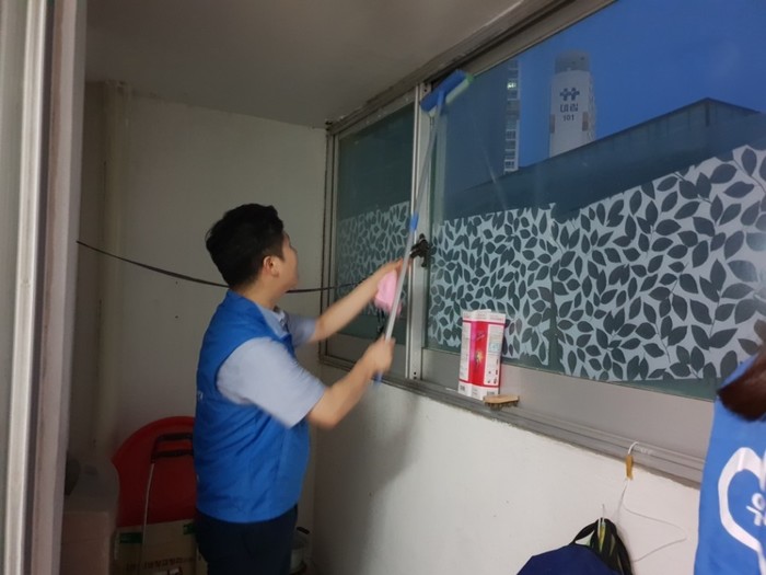 우리은행 남자 직원이 유리창 밀대로 베란다 유리창 청소를 하고 있는 사진
