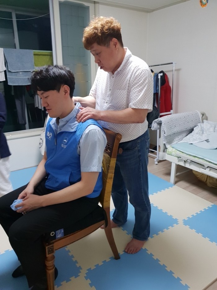 일을 끝낸 은행 직원에게 체험 홈 입주자 김기한씨가 잠깐 어깨를 풀어주고있는 사진