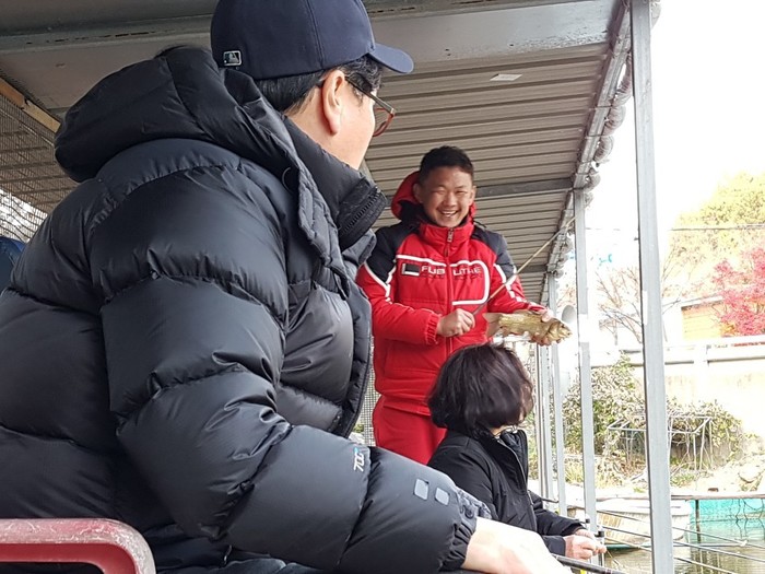 김태우 입주자가 큼직한 붕어를 낙아올려 손으로잡고 활짝 웃고 있는 사진  