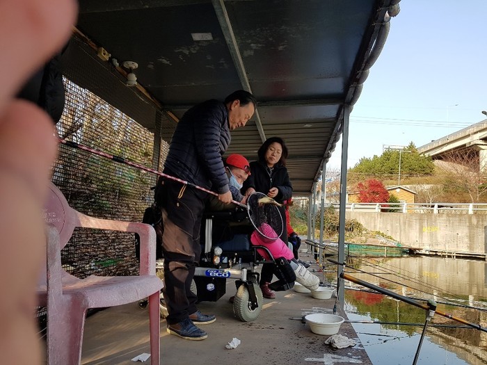 낚시터 사장이 큰 붕어를 잡아 전연식씨에게 보여주는 사진 