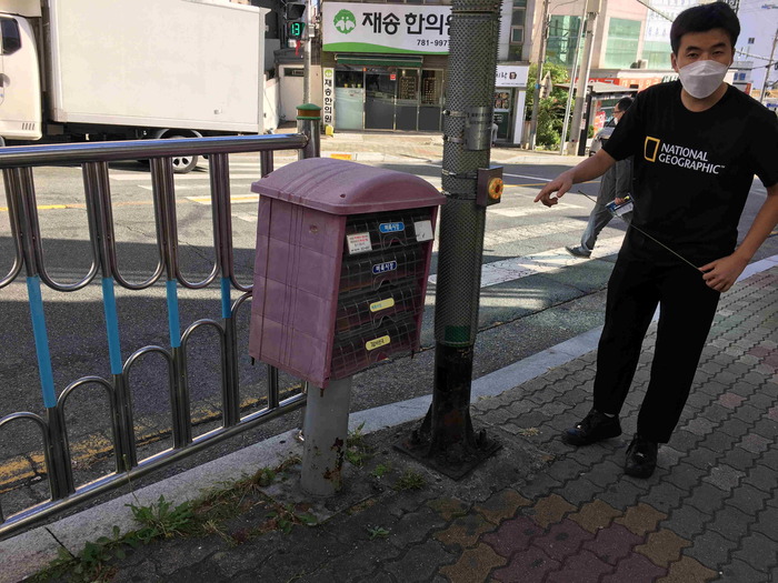 음향신호기 앞에 활동가가 서 있고 근처에 홍보물함이 있는 모습 음향신호기 앞에 활동가가 서 있고 근처에 홍보물함이 있는 모습