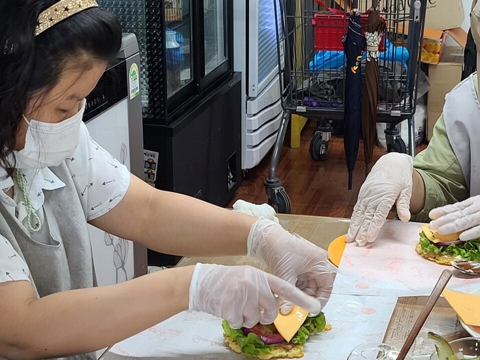 밥패티위에 치즈를 놓고 있는 영신씨 밥패티위에 치즈를 놓고 있는 영신씨