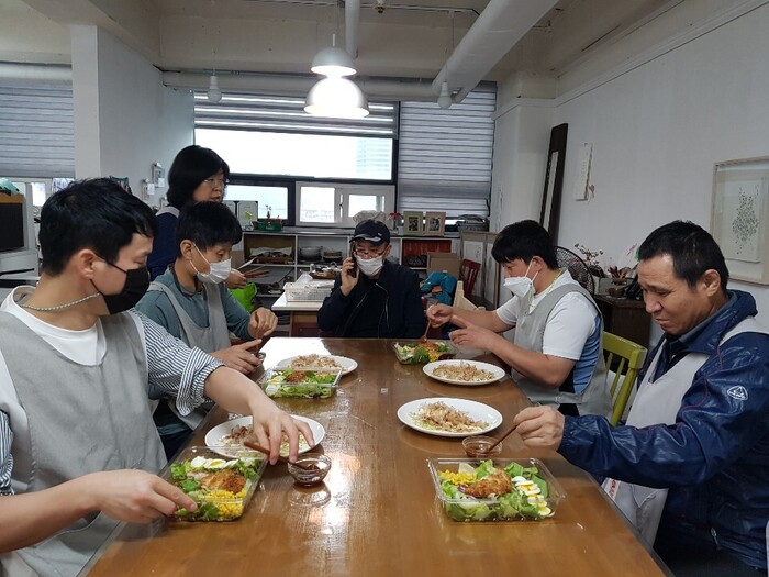 체험홈 식구들 한자리에 앉아 본인들이 요리한 음식 오코노 미야끼, 돈까스 샐러드 먹는사진