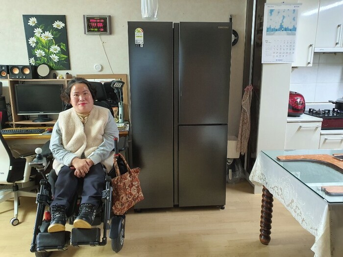 냉장고앞에서 휠체어를 타고 웃고 있는 추수정씨 사진