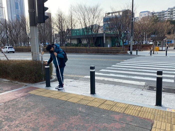 건널목과 멀리 떨어져있는 점자블록, 볼라드 및 음향신호기의 모습 건널목과 멀리 떨어져있는 점자블록, 볼라드 및 음향신호기의 모습