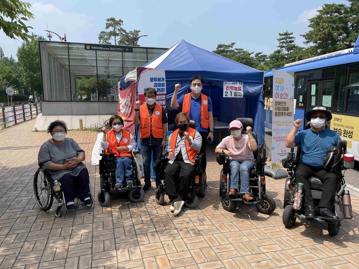 천막 앞에 8명이 일렬로 서서 팔을 올리고 있는 모습 천막 앞에 8명이 일렬로 서서 팔을 올리고 있는 모습