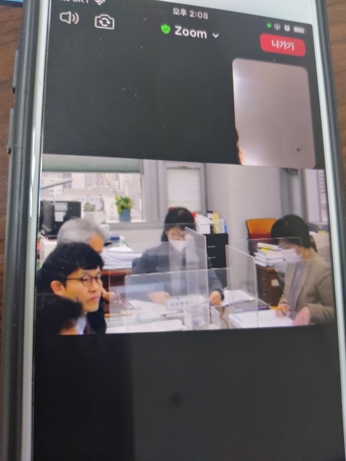 휴내폰으로 zoom을 이용해 회의를 하고 있는 사진