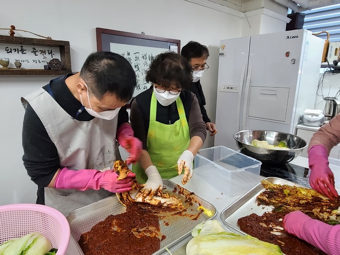 이강이씨 자원봉사자 도움으로 배추에 양념을 바르는 사진 이강이씨 자원봉사자 도움으로 배추에 양념을 바르는 사진