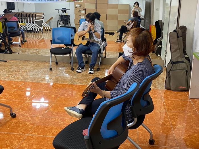 기타를 연습하고 있고, 스마트폰으로 반주를 듣고 있는 회원들 모습